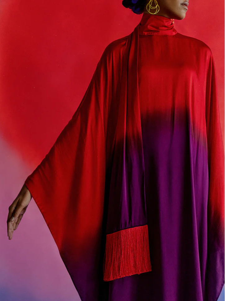A model wearing a Leheriya Round Collar Dress with kimono sleeves and a fringe detail, in ombré colors transitioning from red to purple.